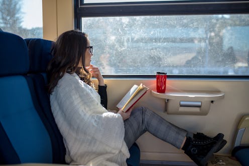Enjoying travel. Young pretty woman traveling by the train near the window. Train Concept.