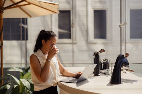 Young Thai woman drinking coffee while reading an e-mail on a computer in coffee shop.