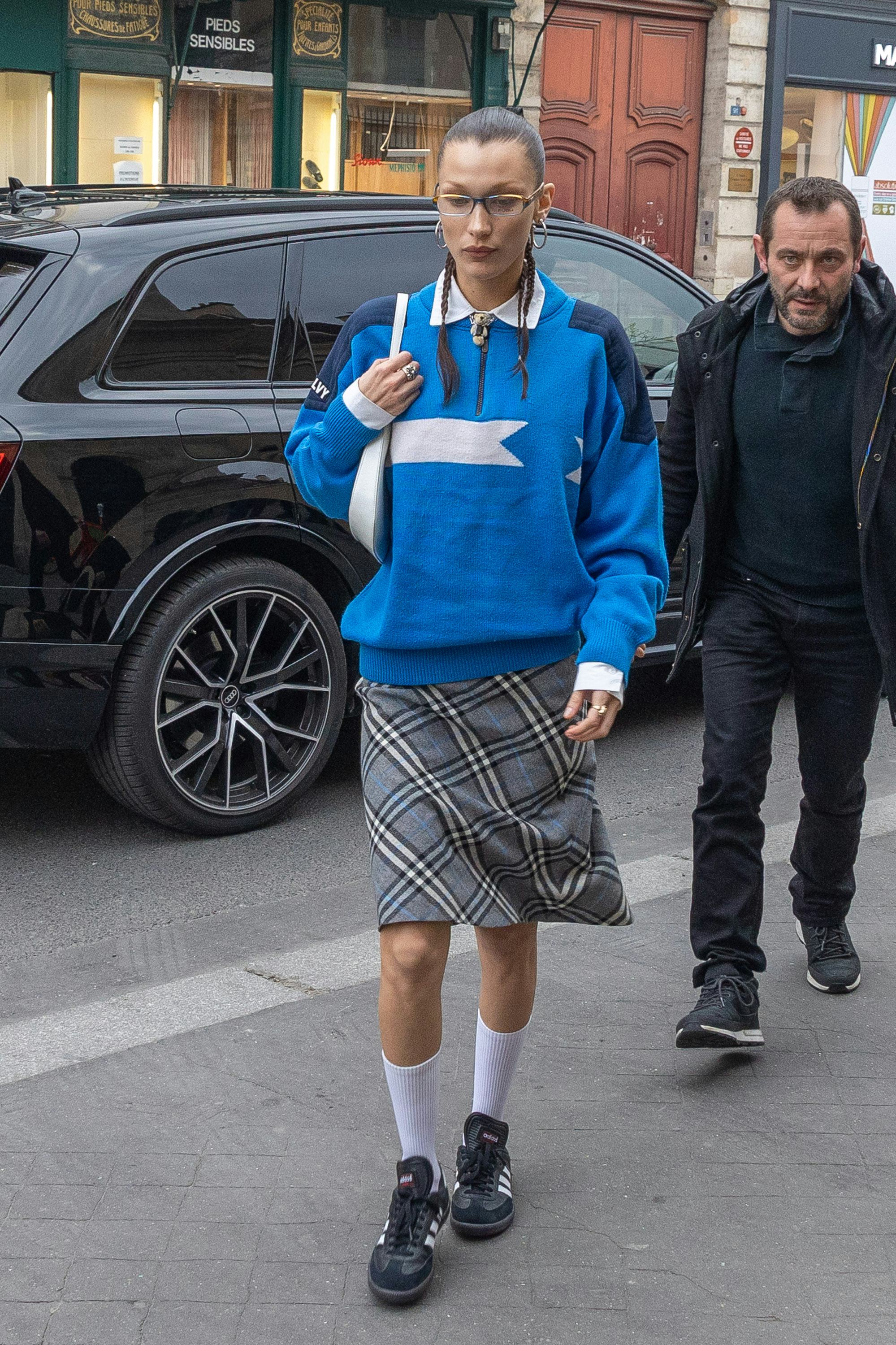 Bella Hadid wears a blue sweater, plaid skirt, and black sneakers on March 04, 2022 in Paris, France&hellip;