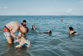 A loving Caucasian father stands in the shallow ocean and plays with his Eurasian one year old son w...