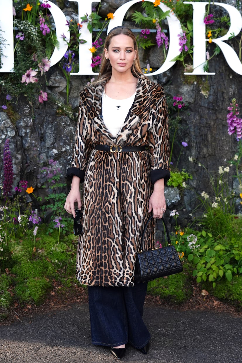 Jennifer Lawrence wears a leopard fur coat, white tank, and jeans to attend the Dior Cruise 2025 sho...