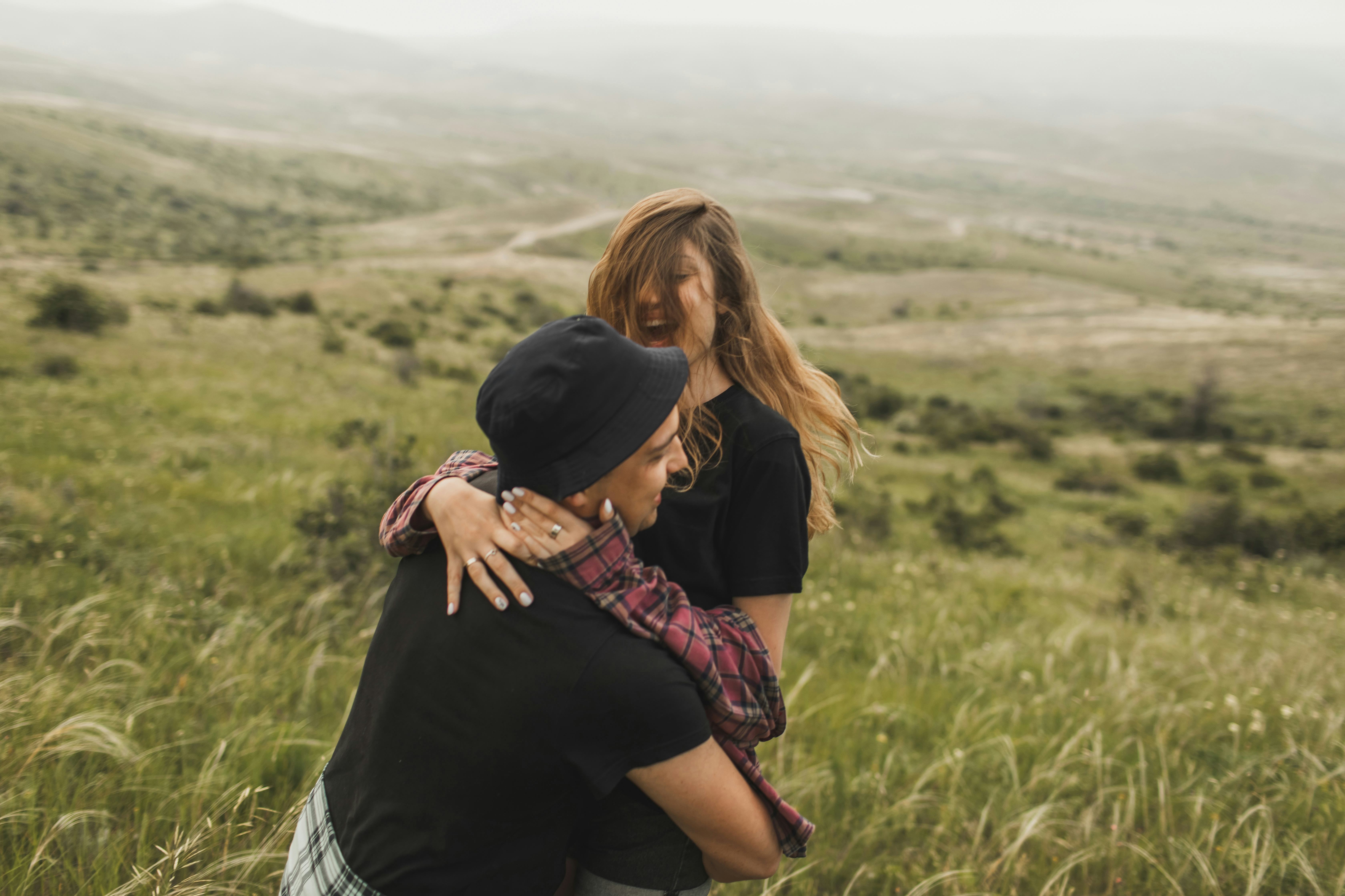 Young couple laughing on a hillside at most likely to questions