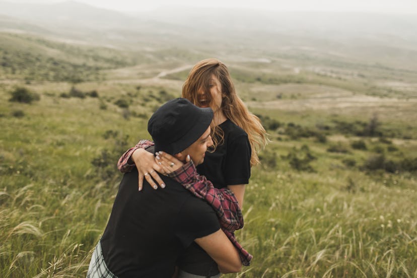 Young couple laughing on a hillside at most likely to questions