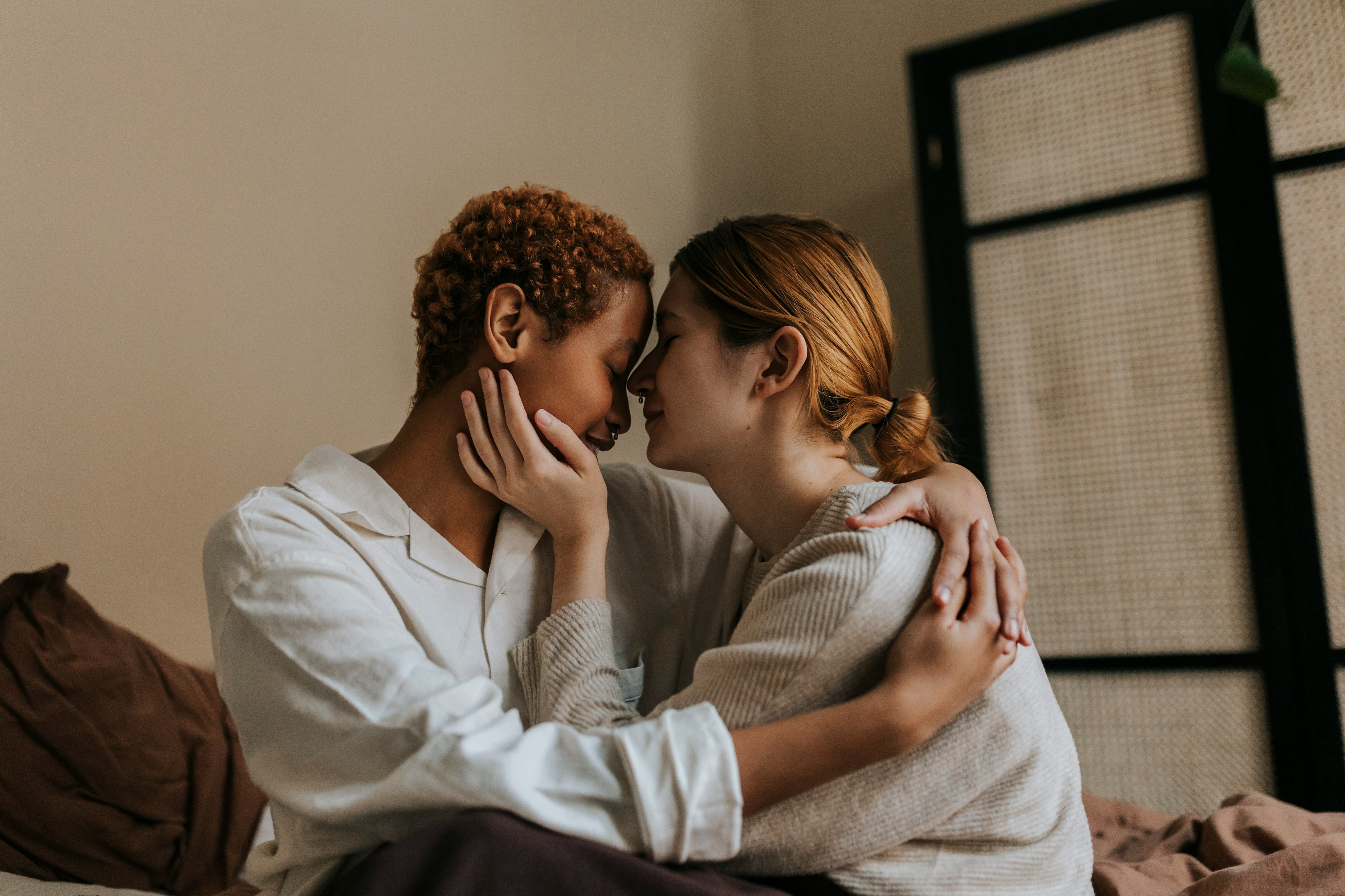 A couple embracing and holding each other&rsquo;s faces on a bed asking each other most likely to question&hellip;