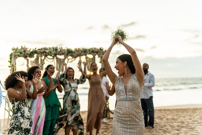 A bride tossing her wedding bouquet and laughing at wedding-related most likely to questions