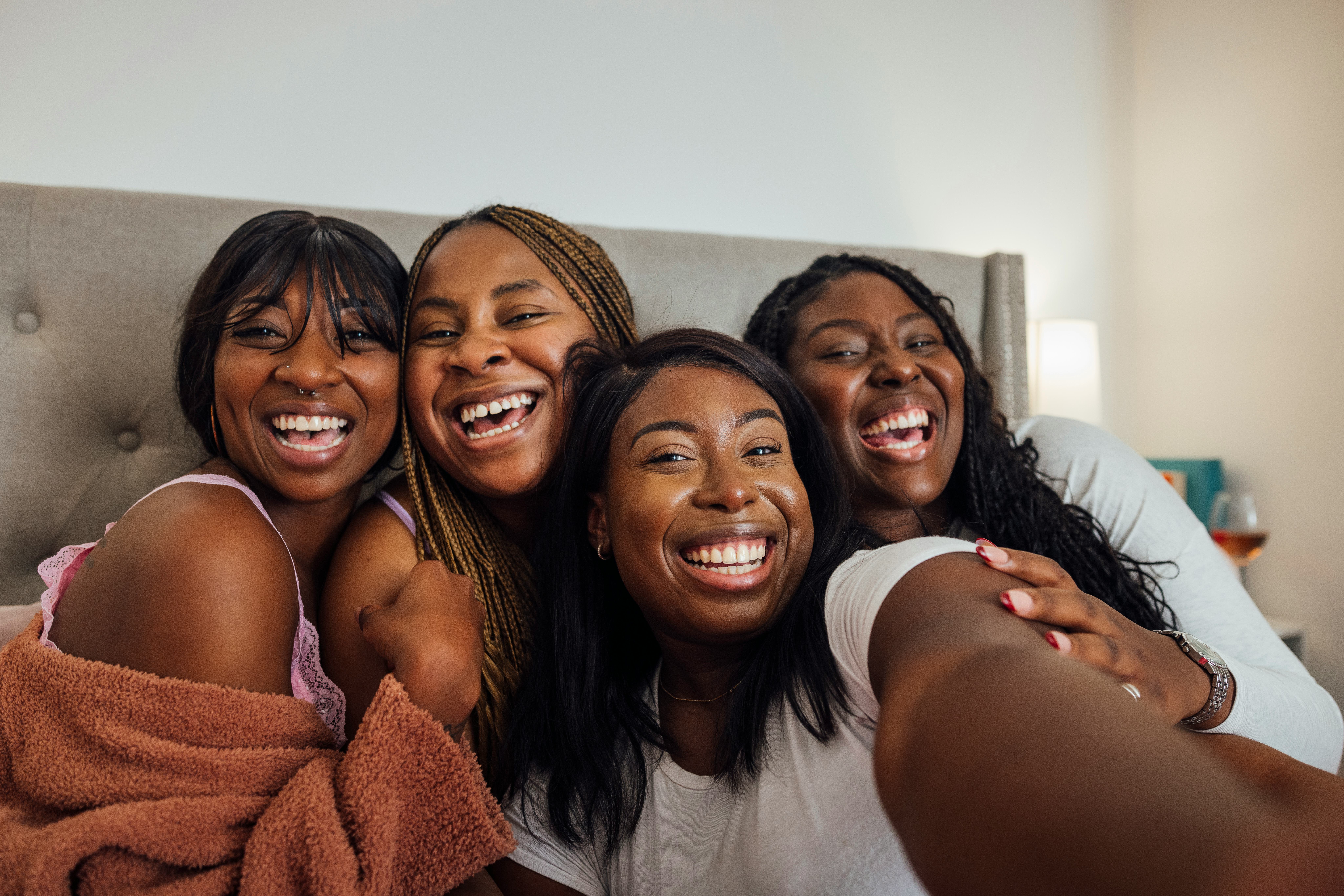 A selfie shot of a group of female friends wearing pyjamas, spending a self-care night together in o...
