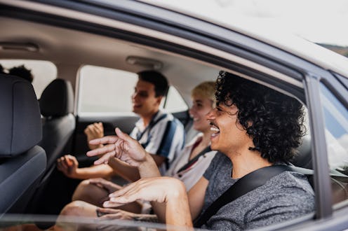 Friends dancing inside a car during a road trip