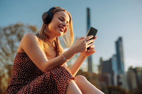 In close-up, a woman uses her smartphone in Central Park, emphasizing technology's role in contempor...