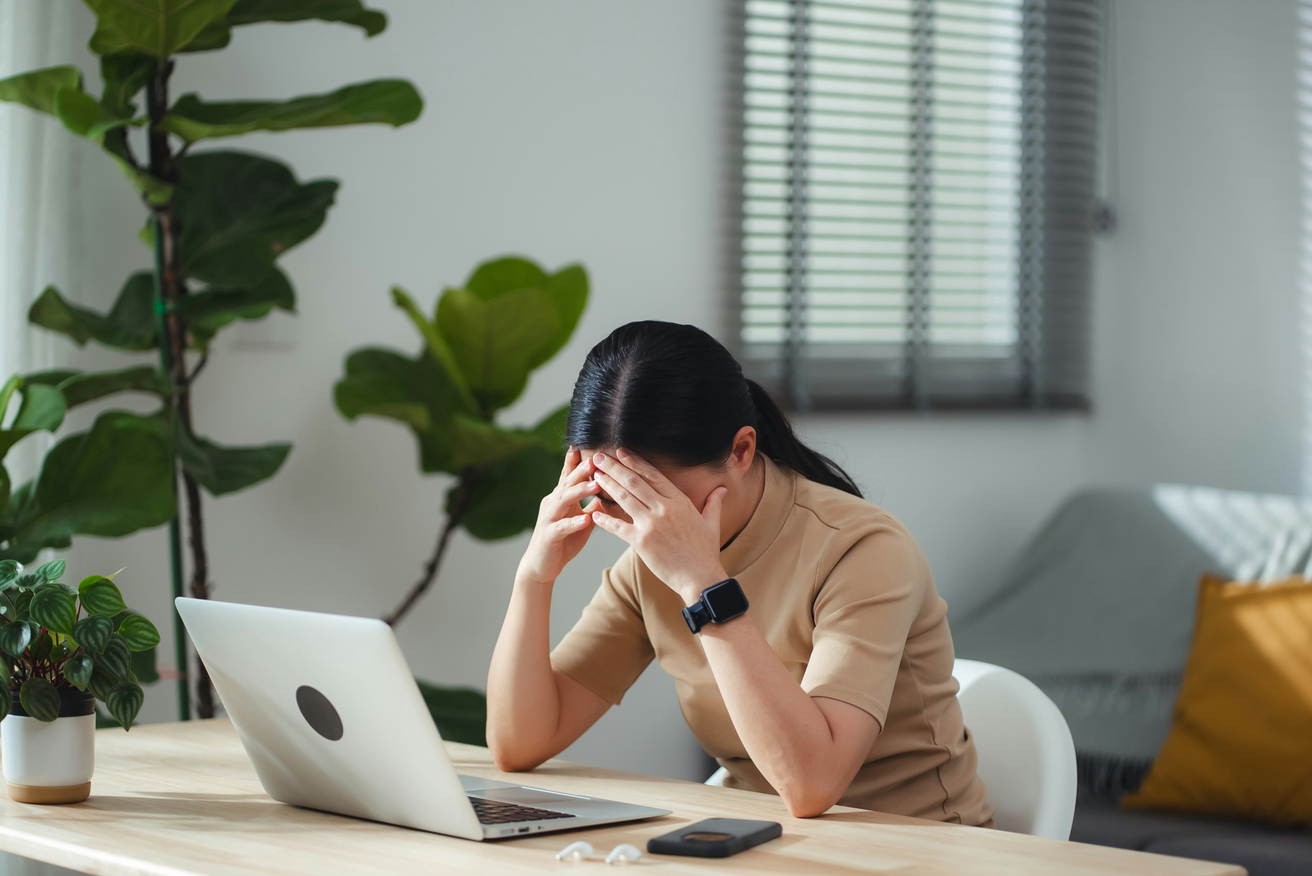 Woman sitting at her desk in her home office using her laptop to look at jokes for adults