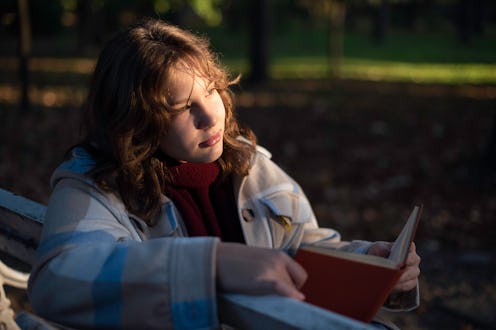 Portrait of a teenage girl reading a book in a city park