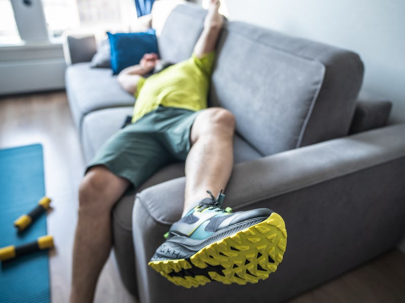 Exhausting home training. Tired man resting on sofa after the morning workout