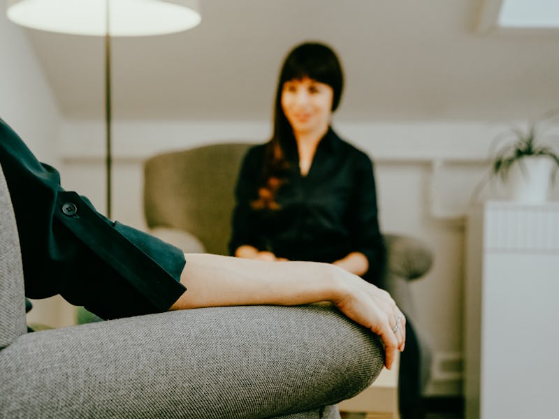 Two women in armchairs are sitting and talking. Woman psychologist practicing with patient women. Co...