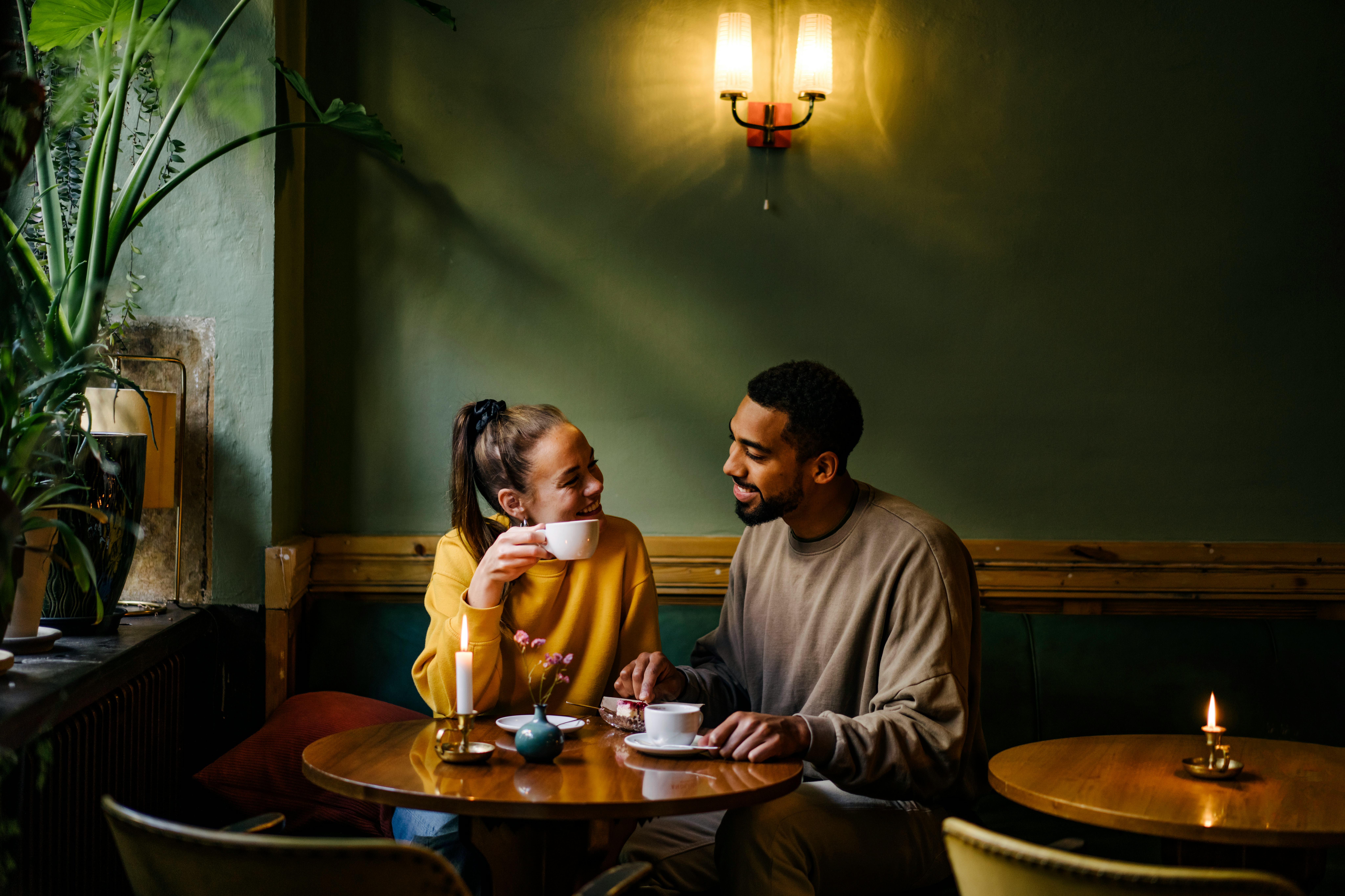A smiling man sitting down next to a woman at a cafe using a pickup line on her as she sips her coff&hellip;