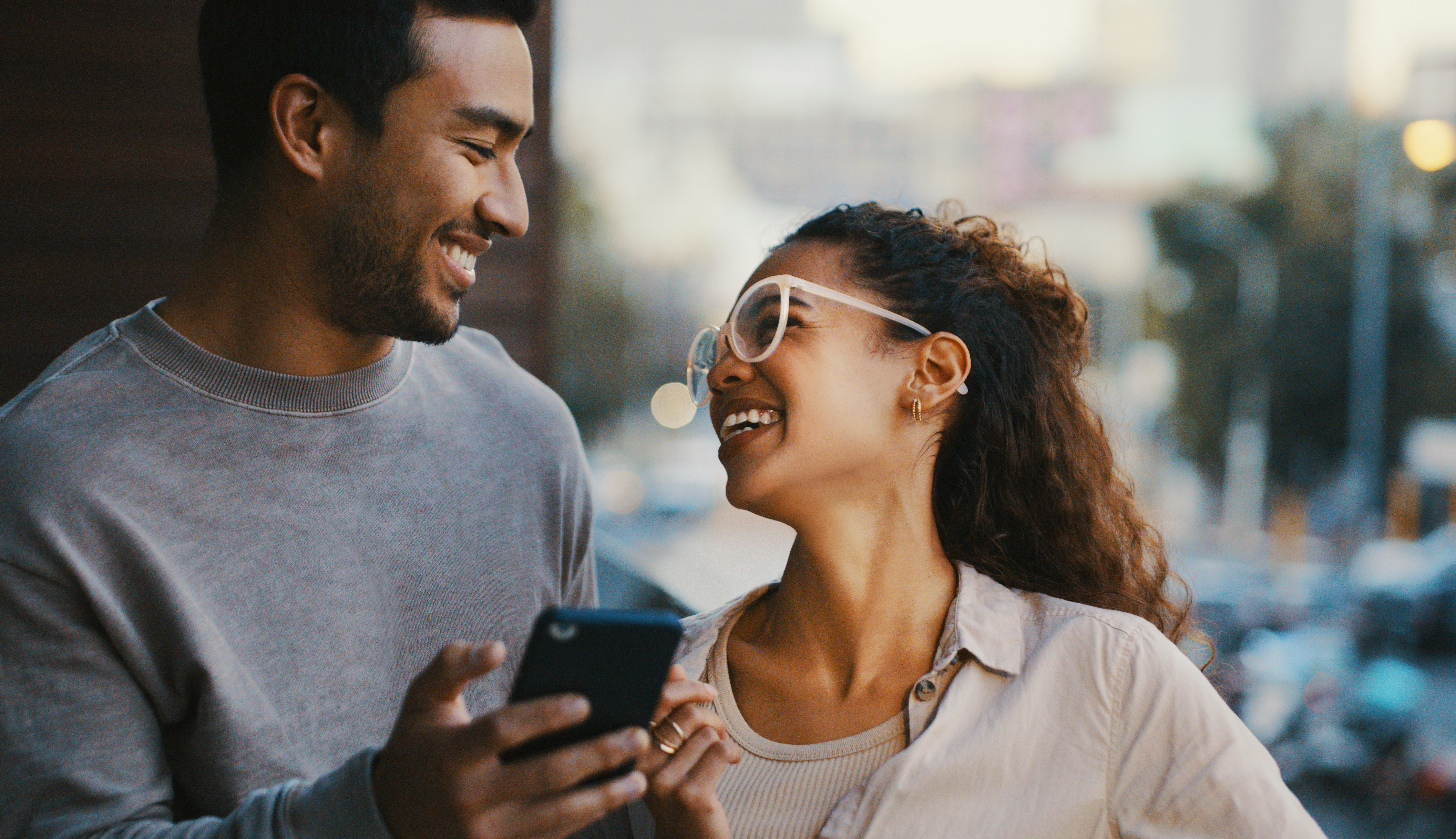 A man and woman smiling at each other after he uses a pickup line on her as they walk down the stree&hellip;