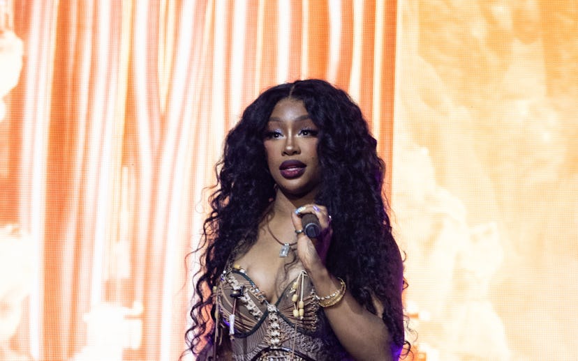 A female performer on stage, wearing an elaborate tribal-inspired costume with a microphone in hand,...