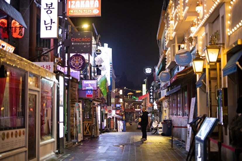 A pub employee waits for a customer on an empty street at night in the Itaewon area of Seoul, South ...