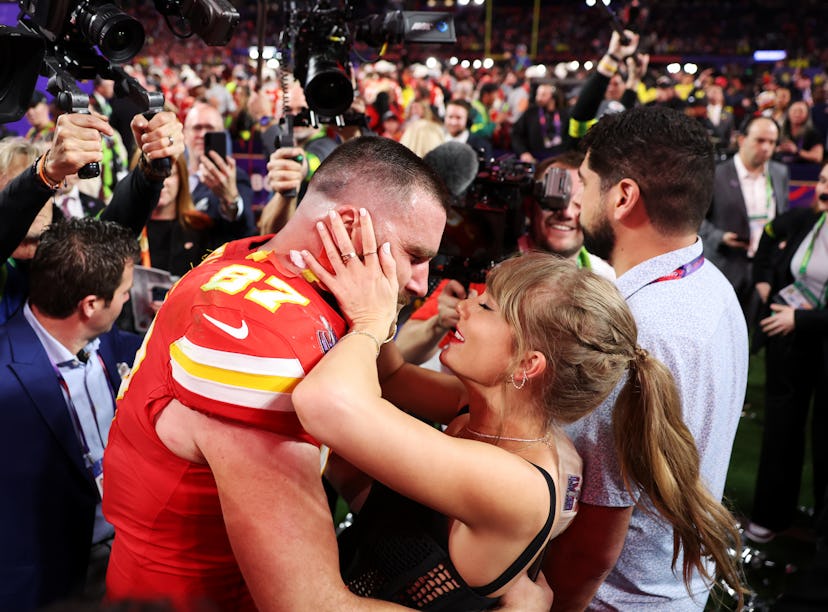 Woman kissing a football player wearing a number 87 jersey among a crowd and cameras at a stadium ev...
