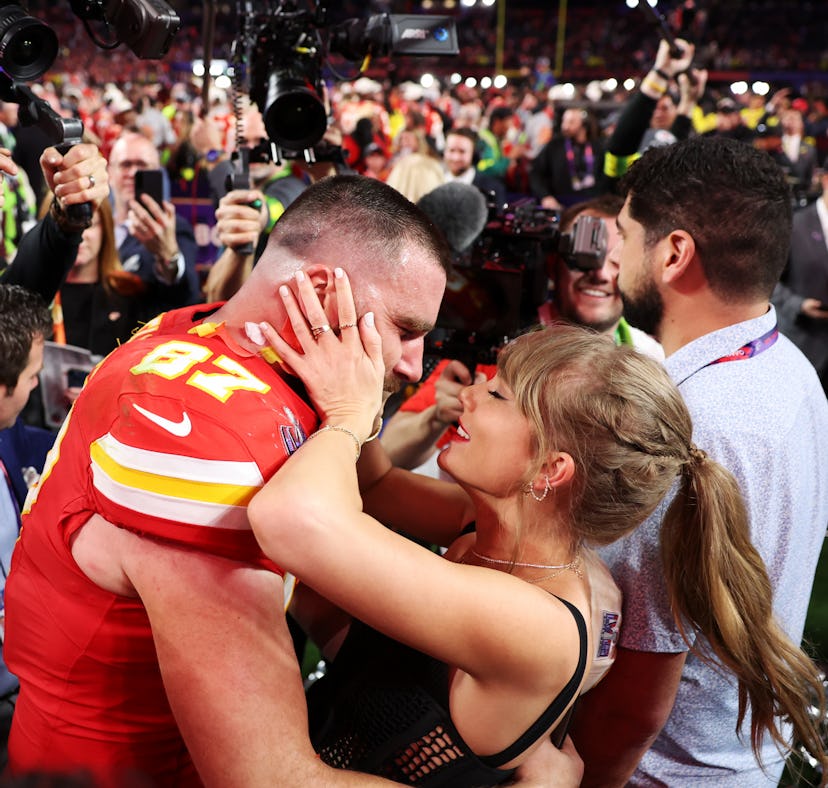 Woman kissing a football player wearing a number 87 jersey among a crowd and cameras at a stadium ev...