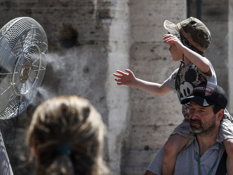 ROME, ITALY - JULY 11: A child refreshes himself at a fan spraying nebulizer water during an intense...
