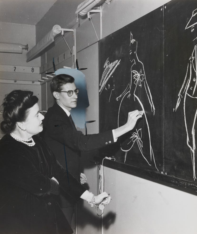 Yves Saint Laurent draws fashion designs on blackboard. A photograph showing Yves Saint Laurent (193...