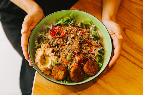 A woman's hands are holding a round plate with a vegetable salad. The concept of healthy food