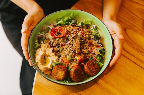 A woman's hands are holding a round plate with a vegetable salad. The concept of healthy food