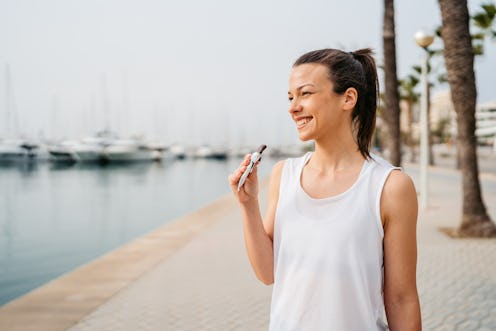 Young Woman eating a protein bar after training on the quayside in Palma de Mallorca in Spain.