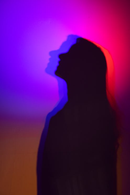 Silhouette of a person against a vibrant red and blue background, creating a dreamy, mysterious effe...