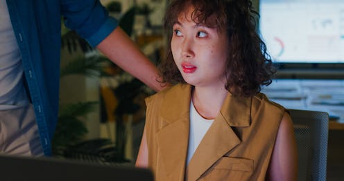 Asian male Manager accusingly expressing displeasure to young female employee suggesting a tense wor...