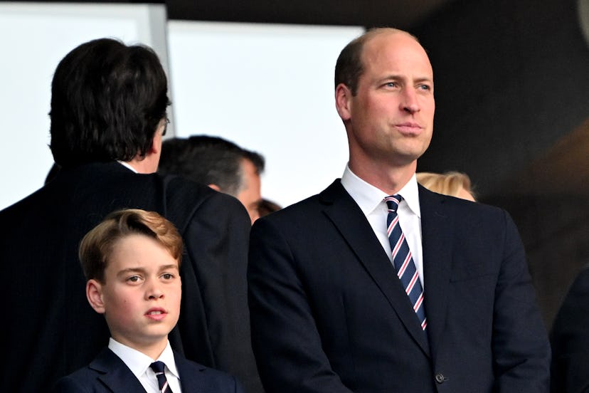 William, Prince of Wales, and his son Prince George stand in the stands before the start of a soccer...