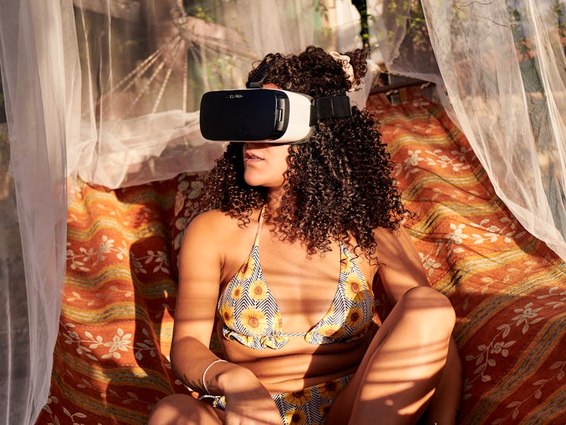 latina with afro hair in a hanging hammock in the sun looking to the side with virtual reality glass...