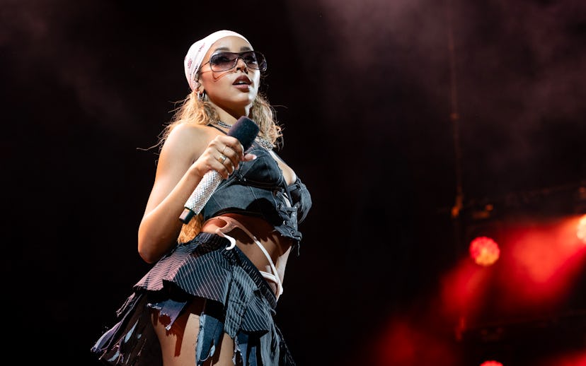 Female singer performing on stage in stylish outfit, wearing glasses and holding a microphone, with ...