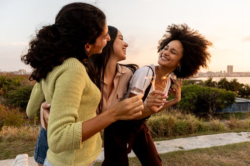 Happy young friends playing with sparkles outdoors