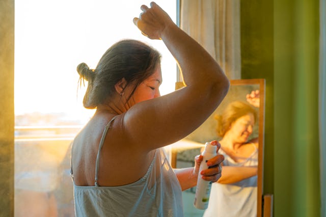 Portrait of woman applying deodorant on underarm, in a story answering the question, do whole body d...