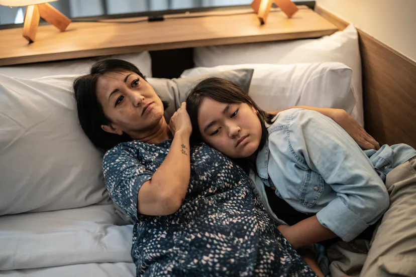 Mother and daughter laying down in bed at home