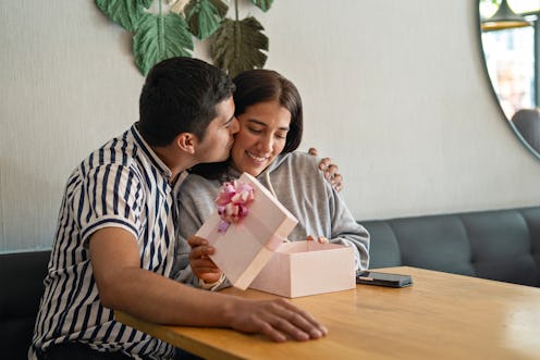 Man giving his girlfriend a Valentine's Day gift or birthday gift at the restaurant or cafe table. S...