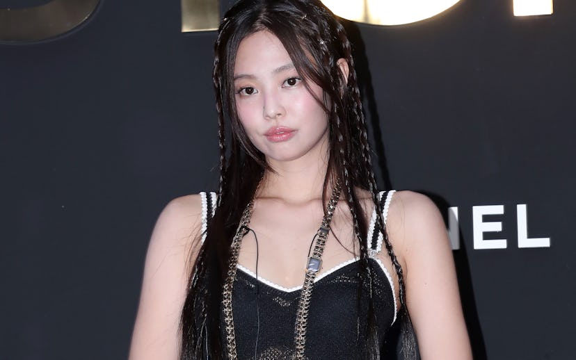 Woman in a sparkly black outfit with braided hair and a small black purse at a Chanel event.