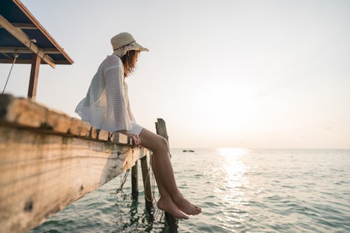 Woman sitting on edge looks out at seaview.