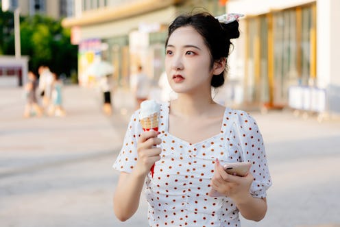 A woman pays with her mobile phone to buy an ice cream at noon in the summer