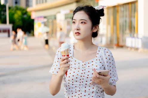 A woman pays with her mobile phone to buy an ice cream at noon in the summer