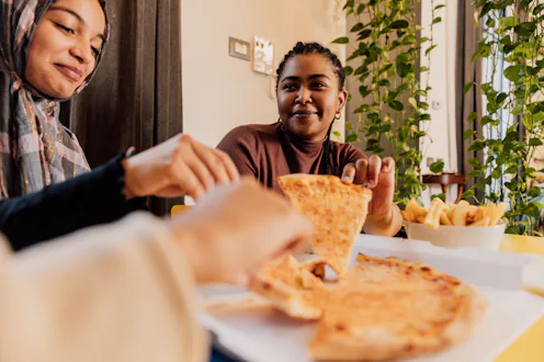 Generation Z friends dining together with pizza and fries.