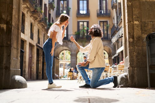 romantic man surprising his girlfriend by asking her to marry him in a public place