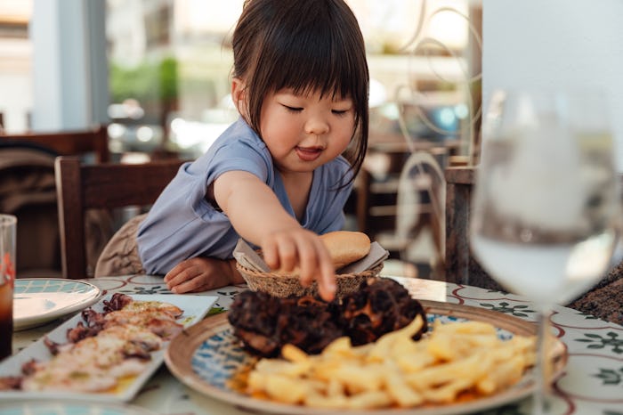 Headshot of hungry little girl eating food at the restaurant.