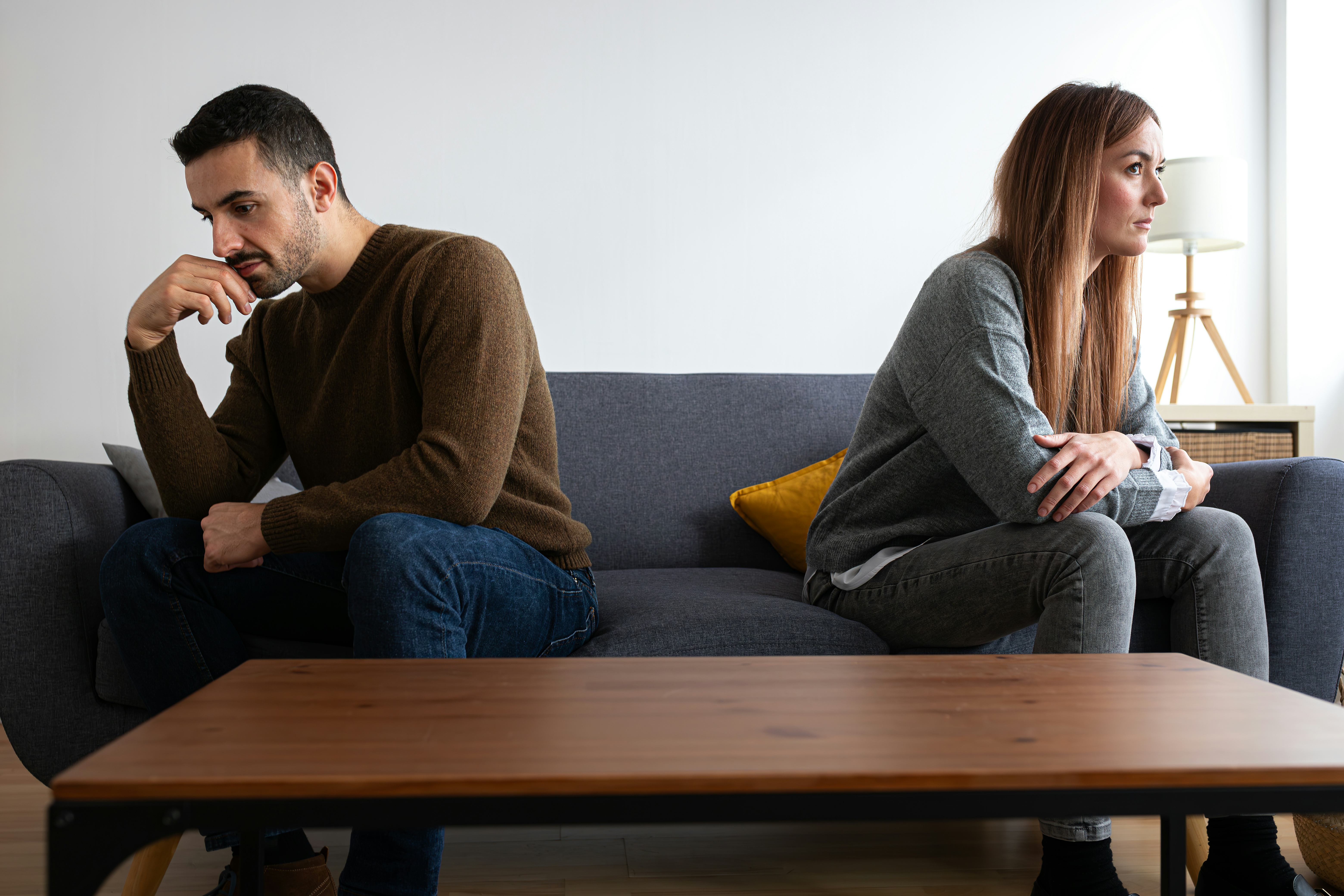 Young couple ignoring each other sitting on the couch