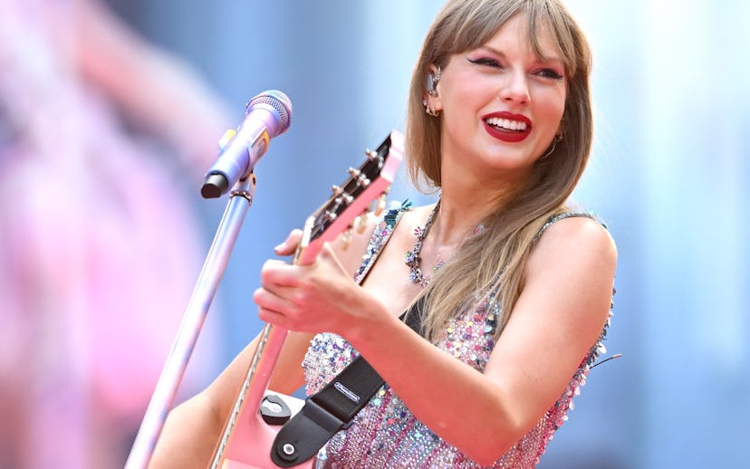 Female musician performing on stage, wearing a sparkling, sleeveless dress and playing a pink acoust...