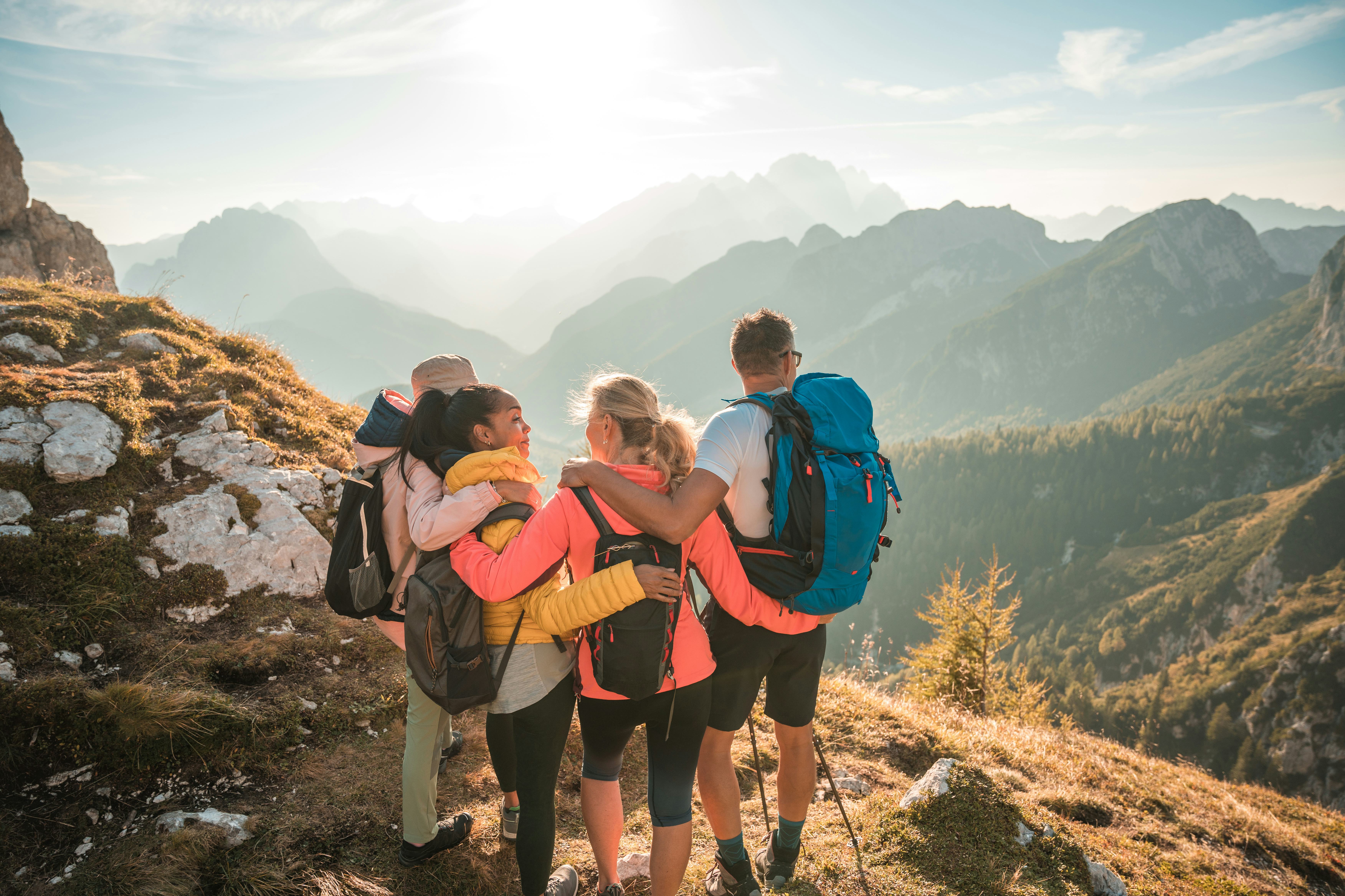 A mountain hike, embraces, has fun, and enjoys the sunny day while looking into the distance