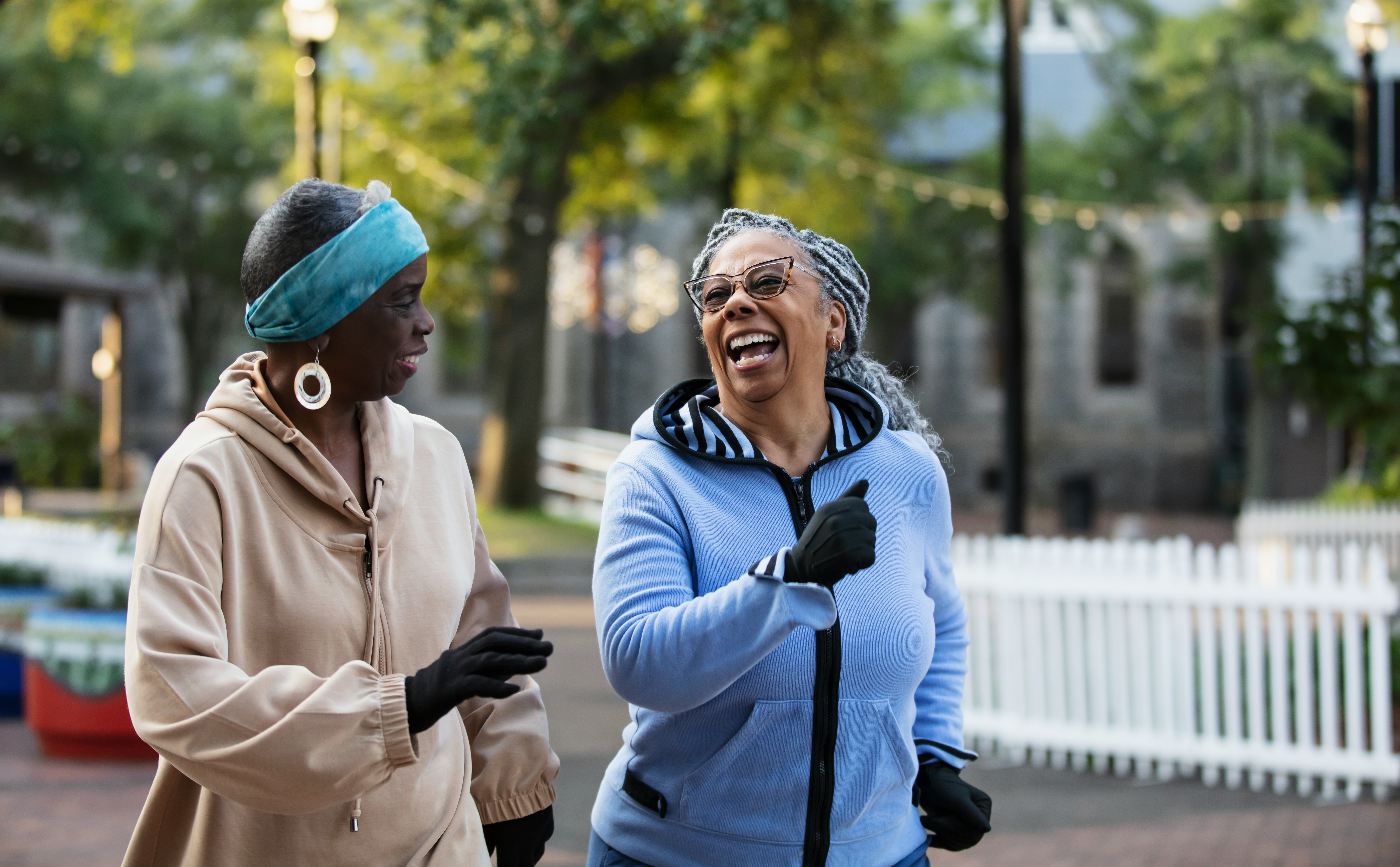 Two senior women exercising together, jogging or power walking in a city park. The African-American &hellip;
