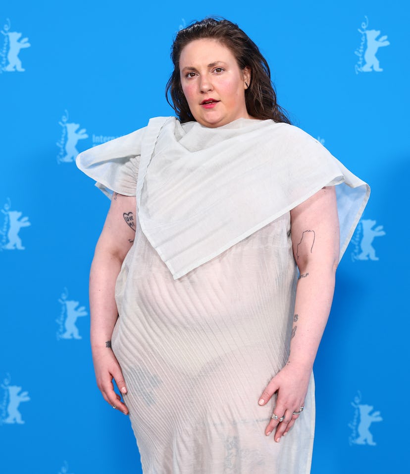 Woman in a unique layered dress poses against a blue backdrop with Berlin Film Festival logos.