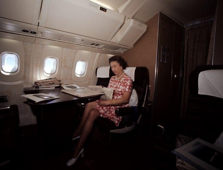The Queen reading newspapers during her flight home from Bridgetown, Barbados, in the supersonic Co...