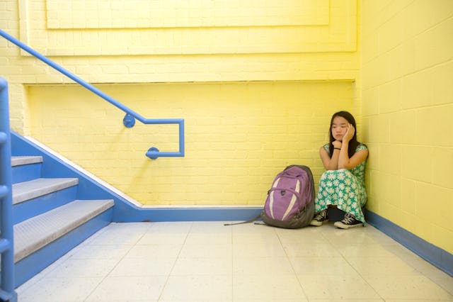 Eleven-year-old girl looks distressed while sitting all be herself in a school stairwell. A mom went...